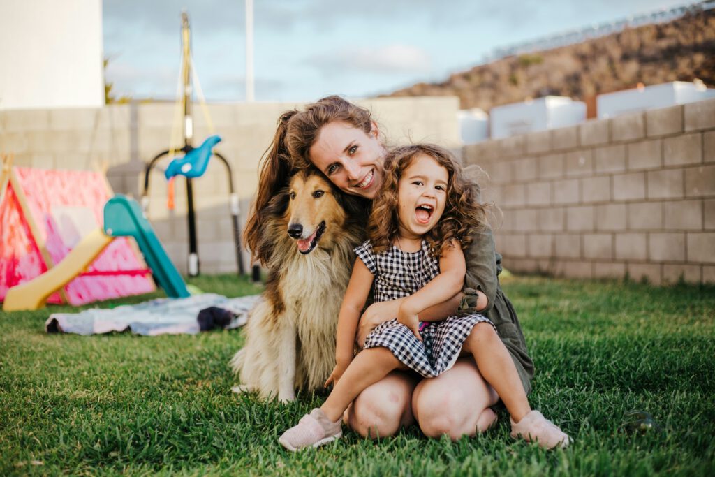 Mutter mit Tochter und Hund im eigenen Garten